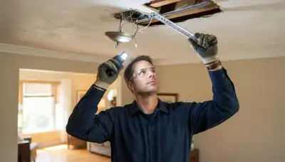 Electrician inspects ceiling box and support brace for safe chandelier installation in Peoria, IL