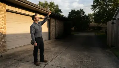 Electrician assesses security light placement on a Peoria, IL home garage eave