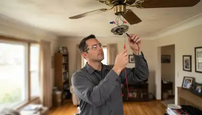 Electrician testing a ceiling fan pull-chain switch with a multimeter during repair in a Peoria, IL home