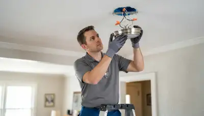 Peoria, IL electrician installing a ceiling light fixture and connecting wiring in a home