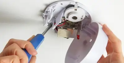 Certified technician wiring smoke detector during installation in Peoria, IL